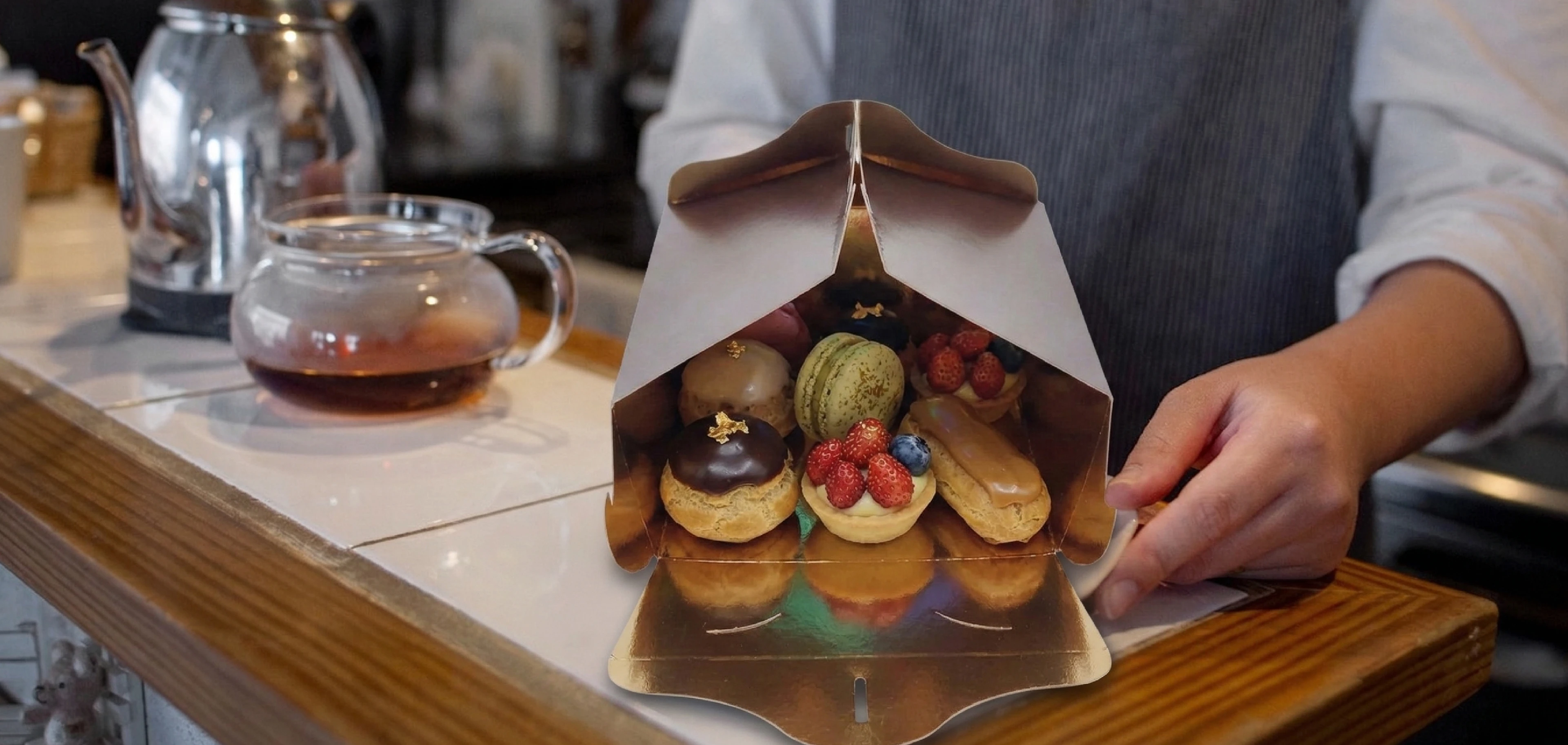 Addetta di pasticceria apre una scatola con pasticcini assortiti, esempio di packaging per pasticceria personalizzato